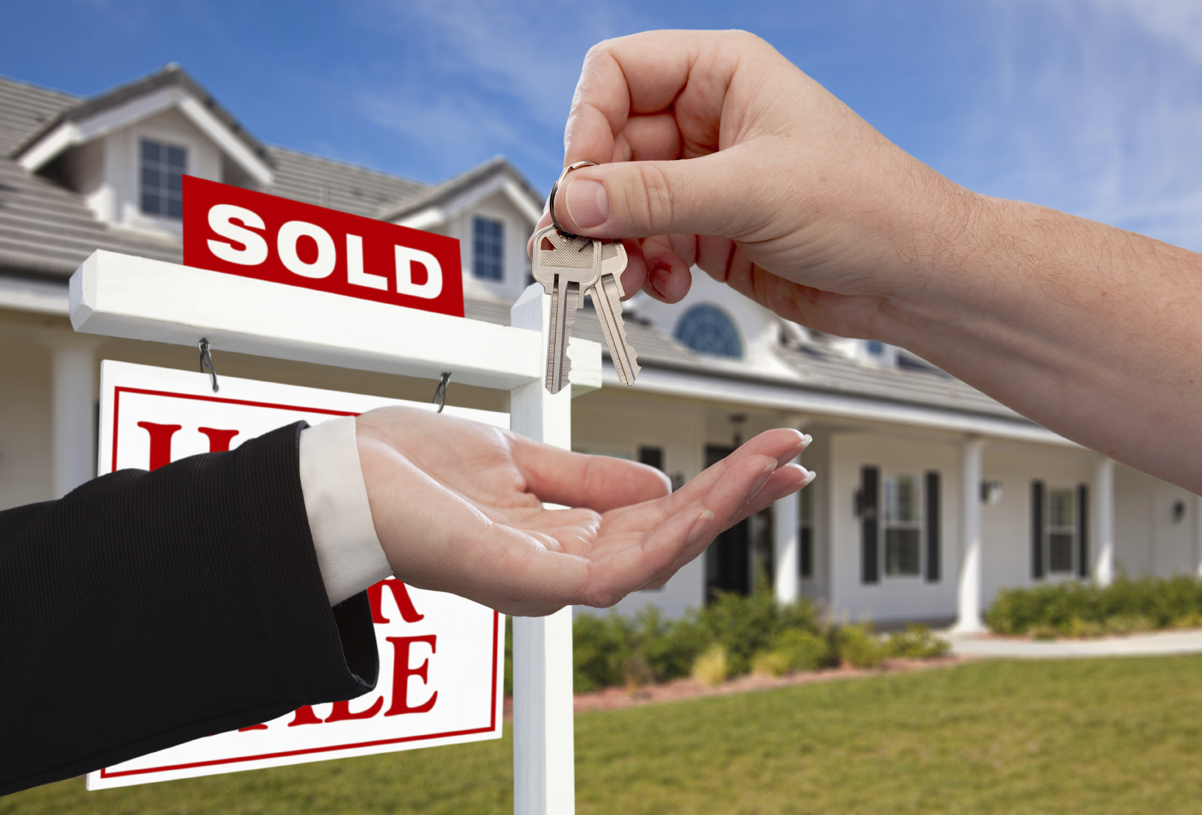 Handing Over the House Keys in Front of Sold New Home Against a Blue Sky